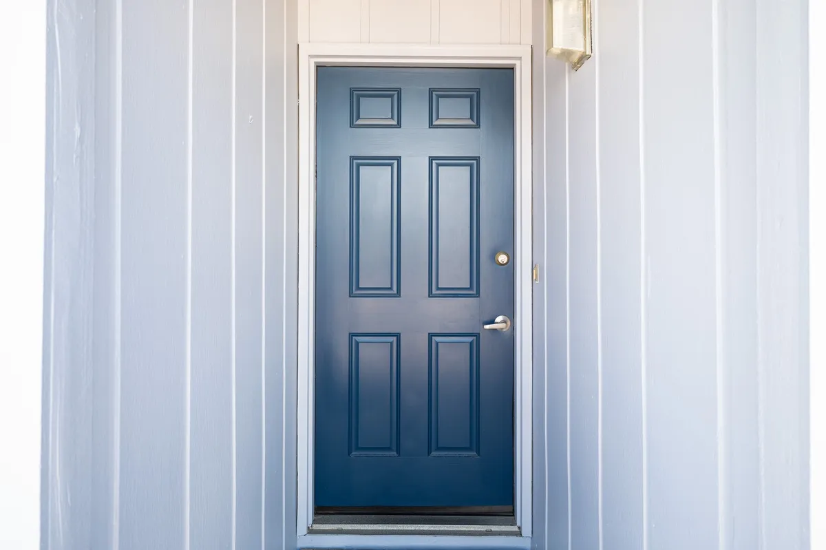 A welcoming blue door and light fixture offer a warm first impression of the Sea Colony property, representing the entrance to your private condo. The inviting exterior ties the narrative of coming home after peaceful local explorations.