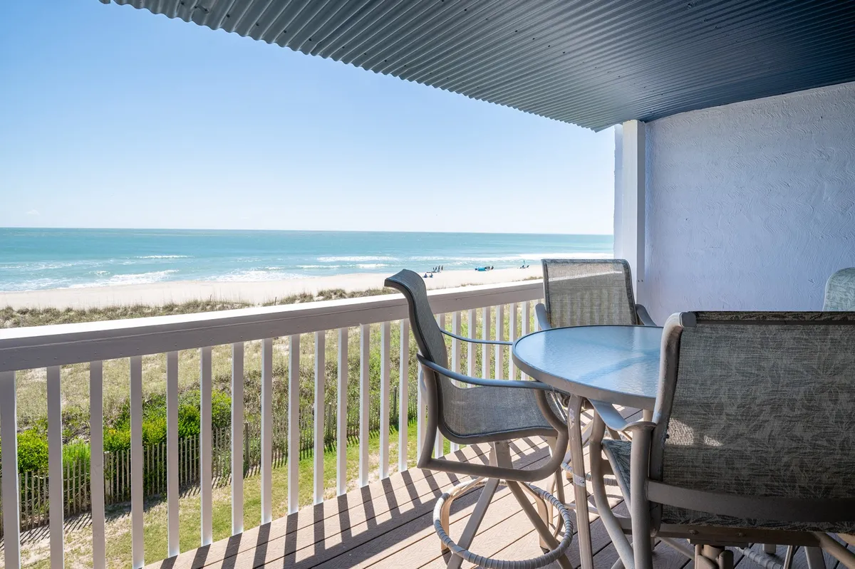 An exterior balcony view featuring comfortable balcony furniture set up for dining, with sweeping views of the ocean and open sky. The mood is serene, ideal for outdoor meals or soaking in the scenery at sunrise or sunset.